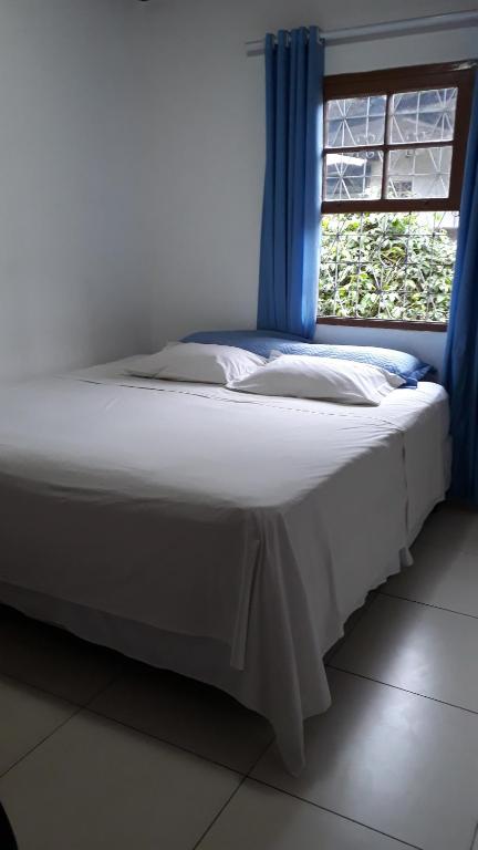 Cama en habitación con ventana en Cantinho Caiçara, en Ilhabela