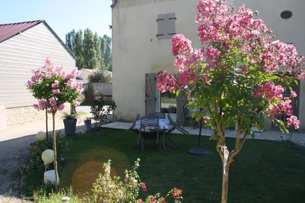 a yard with a table and pink flowering trees at Gite De LA BALLADE in François