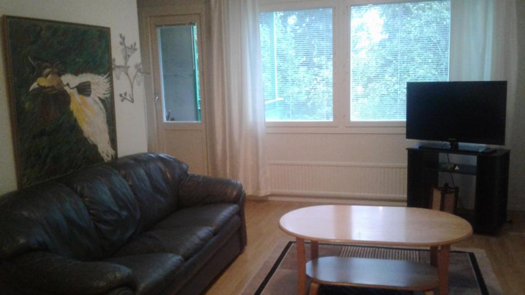 a living room with a leather couch and a table at Varakämppä in Äänekoski