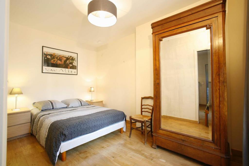 - une chambre avec un lit et un grand miroir dans l'établissement Appartement tout confort au pied du Métro Glacière, à Paris
