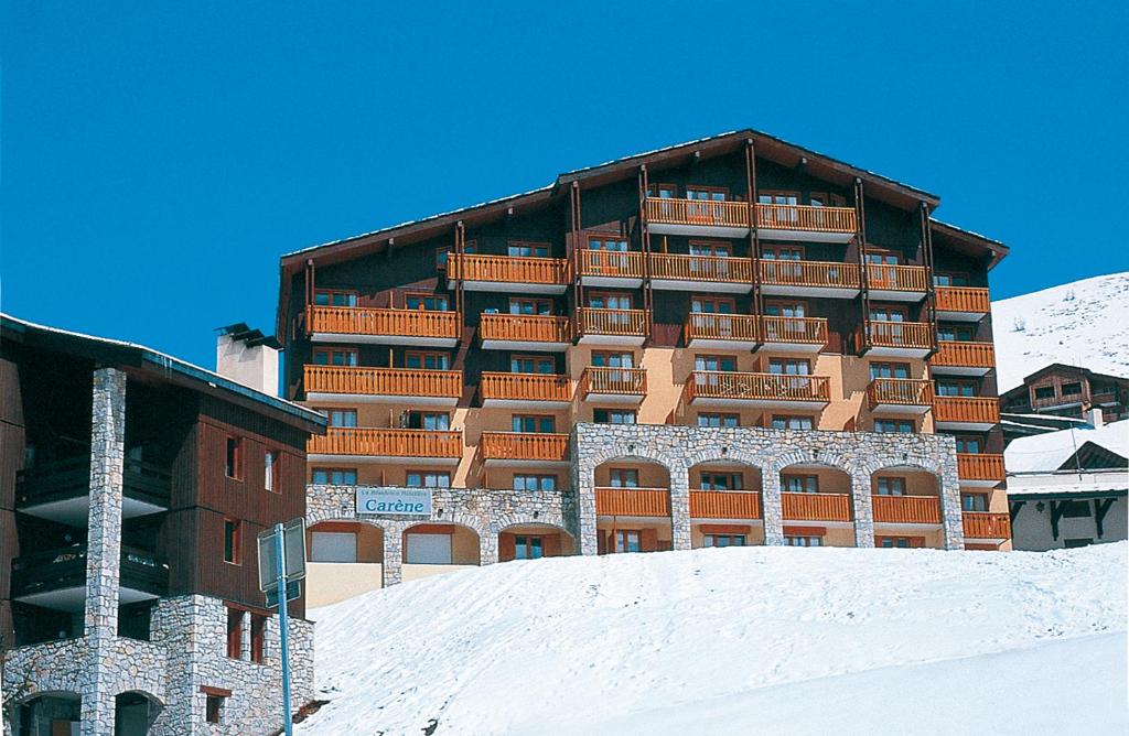 un grand bâtiment au sommet d'une colline enneigée dans l'établissement travelski home classic - Résidence Carène, à Belle Plagne