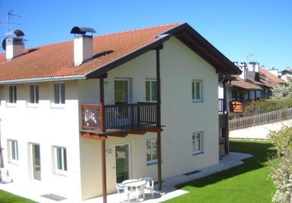 ein weißes Haus mit einem Balkon und einem Hof in der Unterkunft Appartments Am Wiesenrand in Deutschnofen