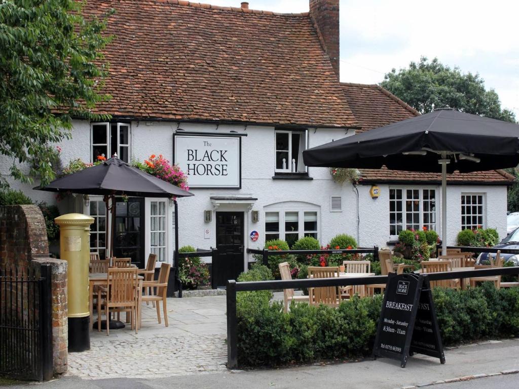 un restaurante de la casa negra con mesas y sombrillas en The Black Horse Fulmer, en Fulmer