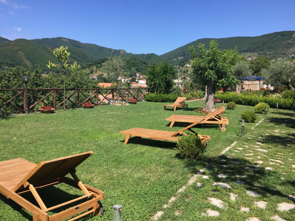 tres mesas de picnic en un campo con montañas en el fondo en B&B Fior Tramonti en Tramonti