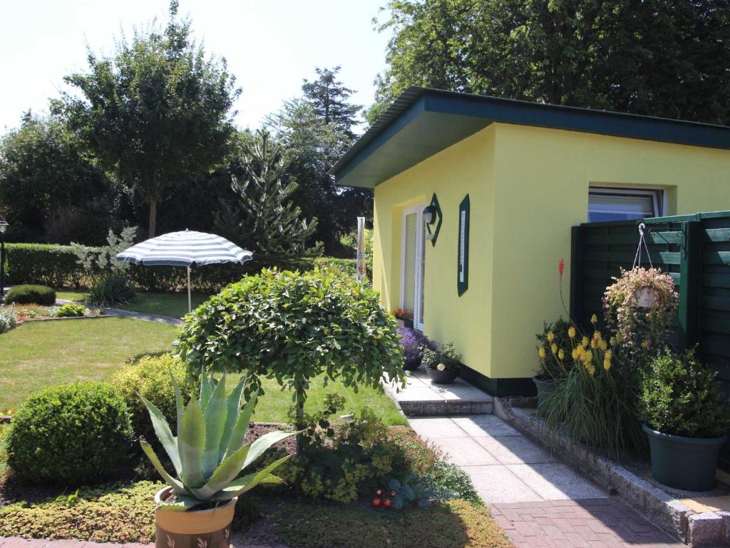 una pequeña casa amarilla con una planta en un patio en Ferienhaus Smerzinski, en Bergen auf Rügen