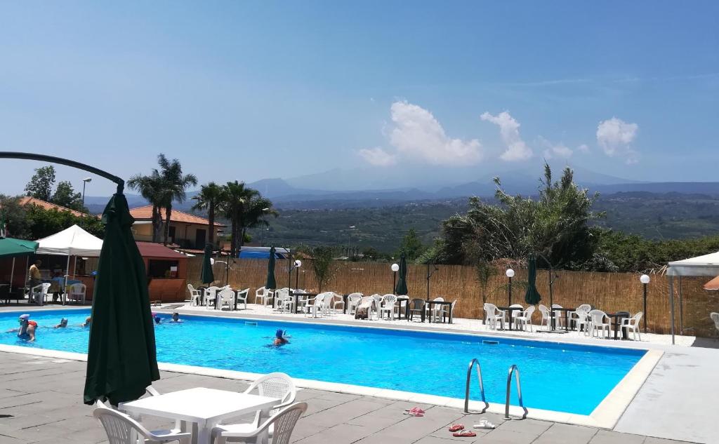 a swimming pool with chairs and a table and an umbrella at Orchidea apartments in Mascali