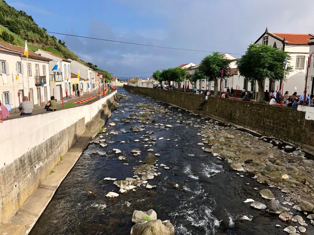 a river full of trash in a town with buildings at Casa Auri in Faial da Terra