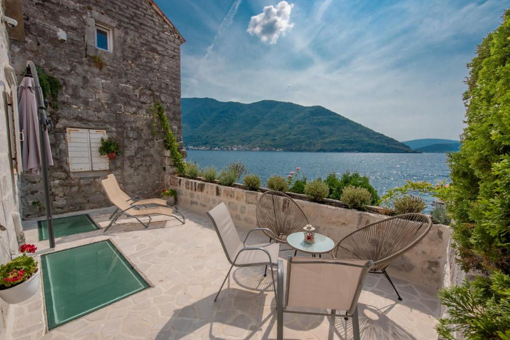 un patio con sillas, una mesa y una masa de agua en Apartment Kula Đurišić, en Perast