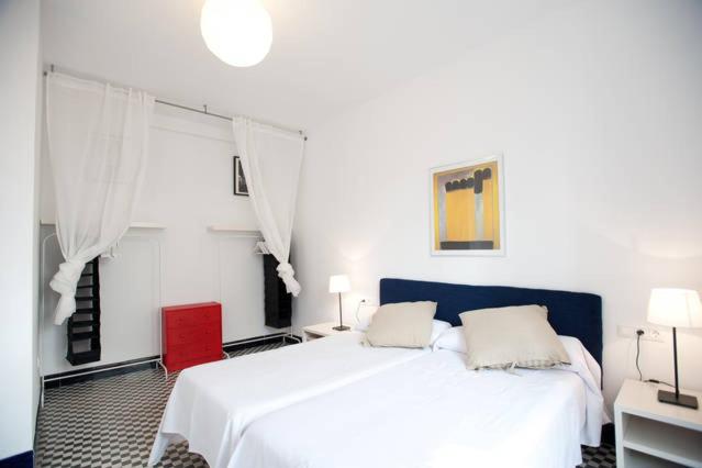 1 dormitorio con 1 cama blanca y 1 silla roja en Apartamentos Calle Rosario, en Sevilla