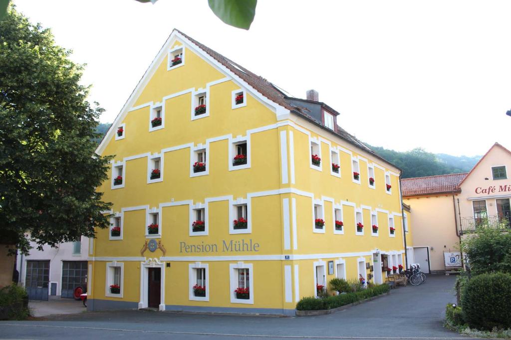 un edificio amarillo con el nombre de un hotel en Pension Mühle, en Egloffstein