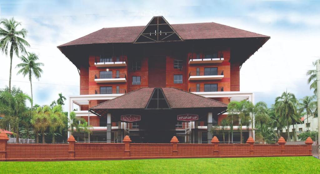 ein großes Hotel mit einem großen Gebäude im Hintergrund in der Unterkunft RNS ONE in Subrahmanya