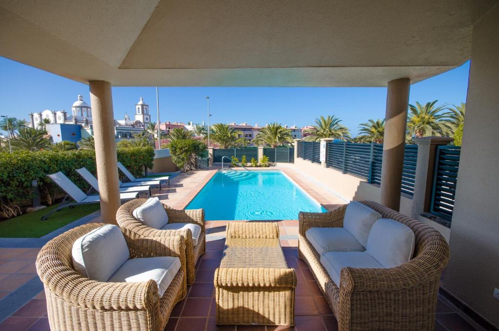 un patio con sillas de mimbre y una piscina en Villa Meloneras, en Meloneras