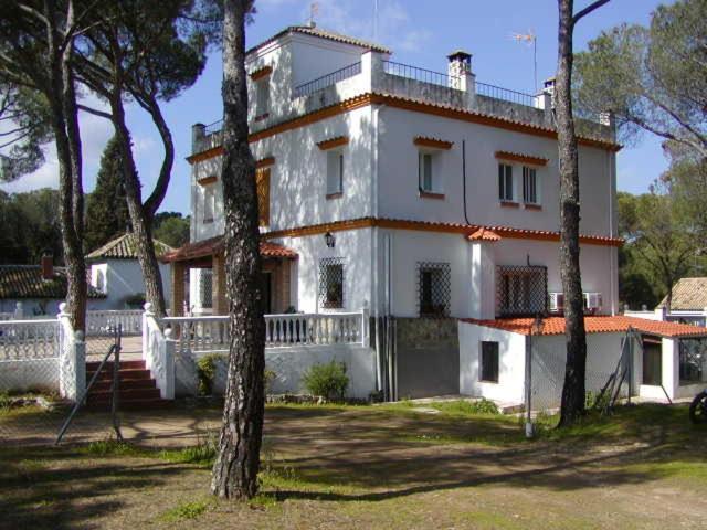 uma grande casa branca com árvores em frente em El Pinar De Villa Carmina em Cerro Muriano