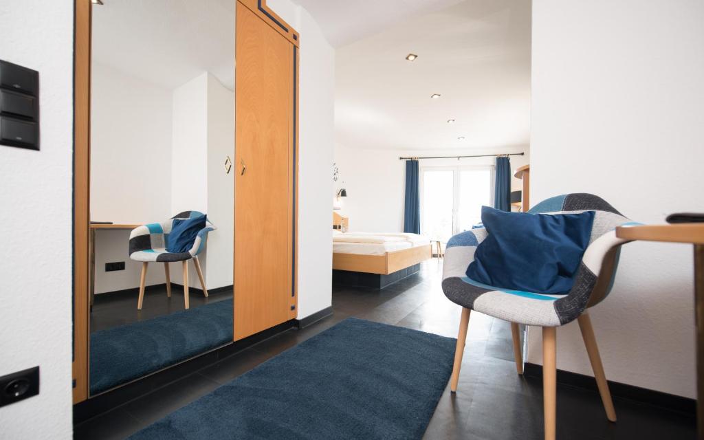 - une chambre avec un miroir, un lit et une chaise dans l'établissement Berghotel Kristall, à Idar-Oberstein