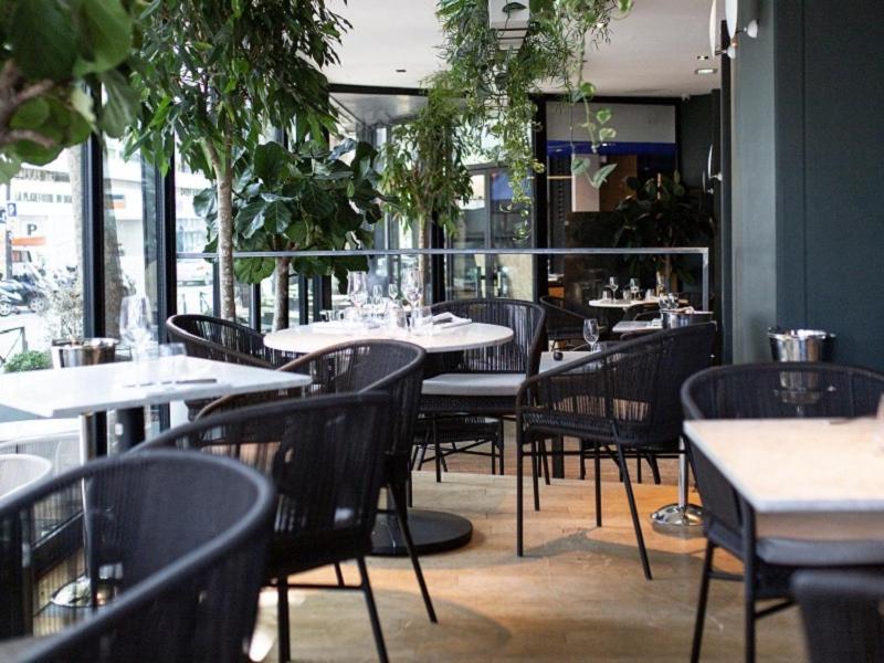 a dining room with tables and chairs and plants at Hotel Square in Paris