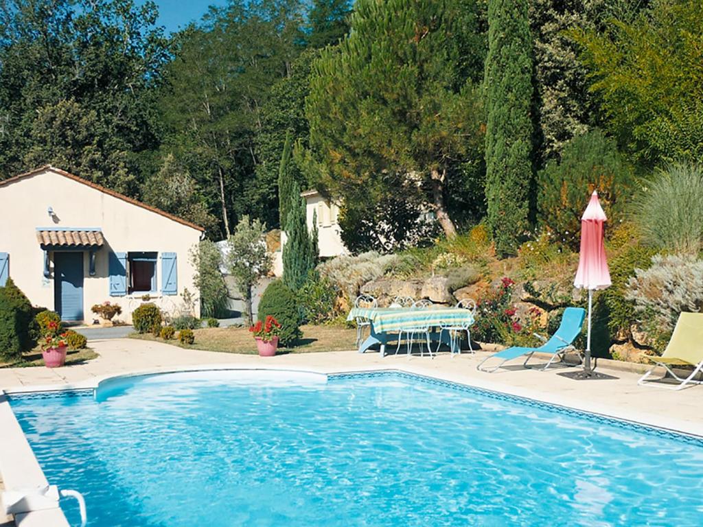 une piscine avec une table, des chaises et un parasol dans l'établissement Appartement Côté Sud vert, à Sarlat-la-Canéda