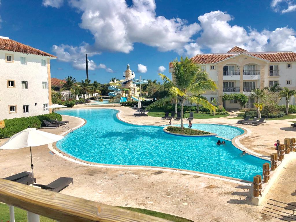 - une piscine dans un complexe avec des palmiers et un bâtiment dans l'établissement Beach Day @CadaquesCaribe Bayahibe, à Bayahibe