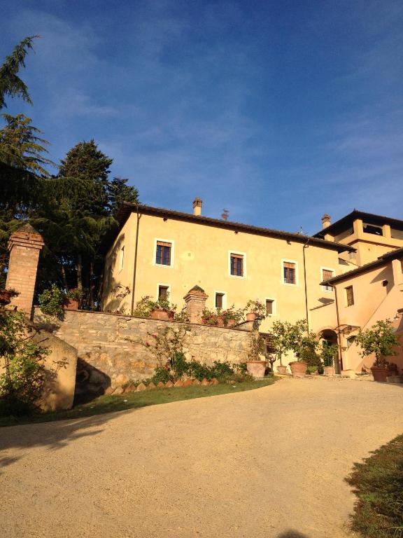 duży biały budynek z kamienną ścianą przed nim w obiekcie Torraccia di Chiusi Agriturismo Relais w mieście San Gimignano
