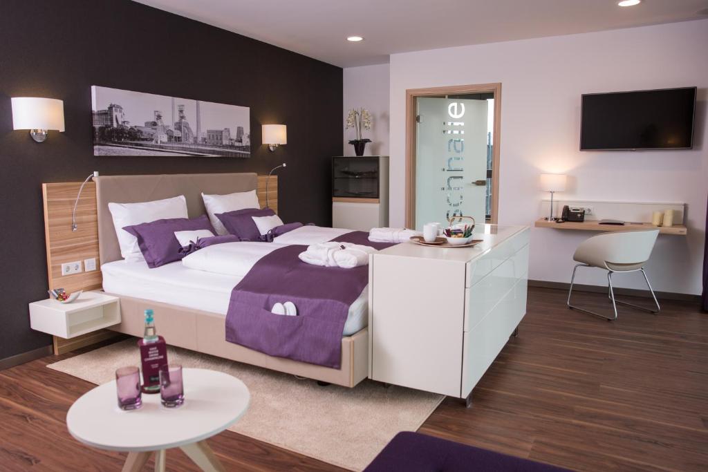 een slaapkamer met een groot bed met paarse kussens bij Heiner's Parkhotel in Gelsenkirchen