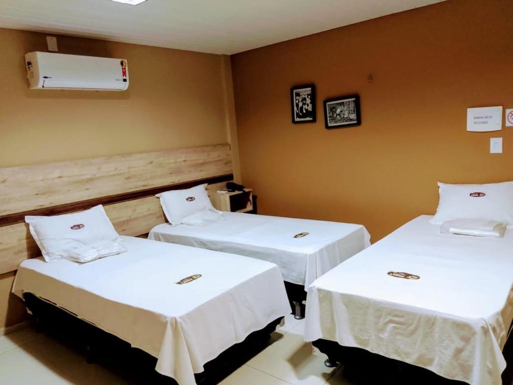 two beds in a room with white sheets at Pousada Café Com Leitte in Juazeiro do Norte
