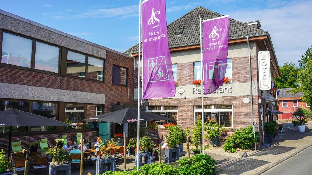 un restaurante con estandartes púrpuras frente a un edificio en dS Hotel Bad Bentheim, en Bad Bentheim
