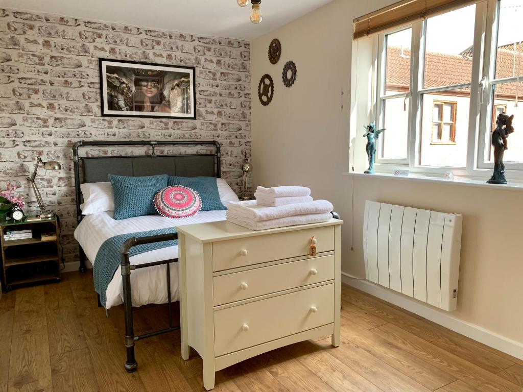 um quarto com uma cama com uma cómoda e uma parede de tijolos em Pristine Apartment in The Centre of Glastonbury em Glastonbury