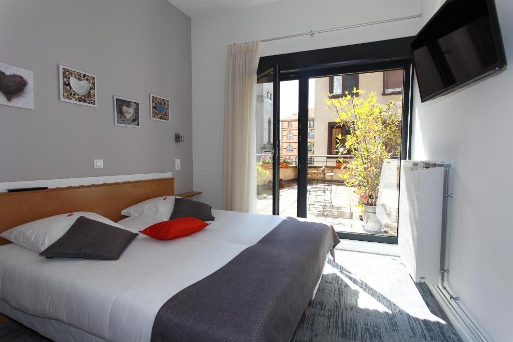 a bedroom with a large bed and a large window at Hôtel De L'Ill in Strasbourg