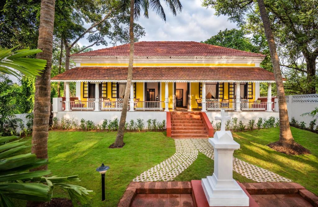 une maison jaune avec des palmiers dans une cour dans l'établissement amã Stays & Trails, Cardozo House, à Candolim