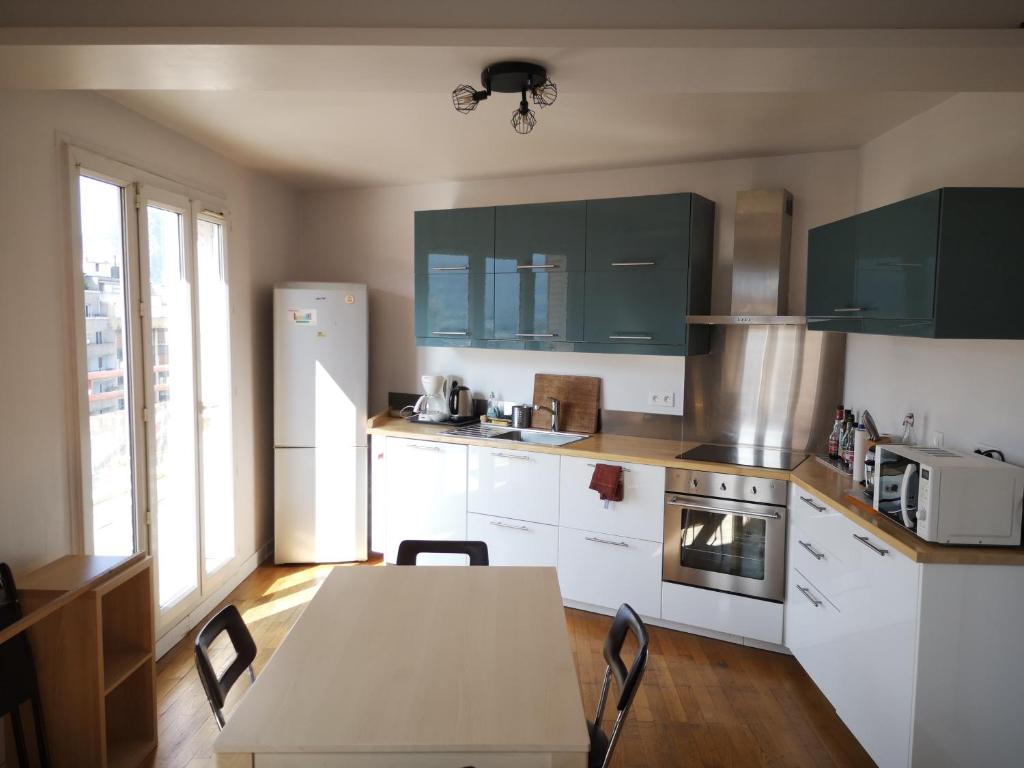 a kitchen with white cabinets and a table with chairs at Les terrasses de Libération in Grenoble