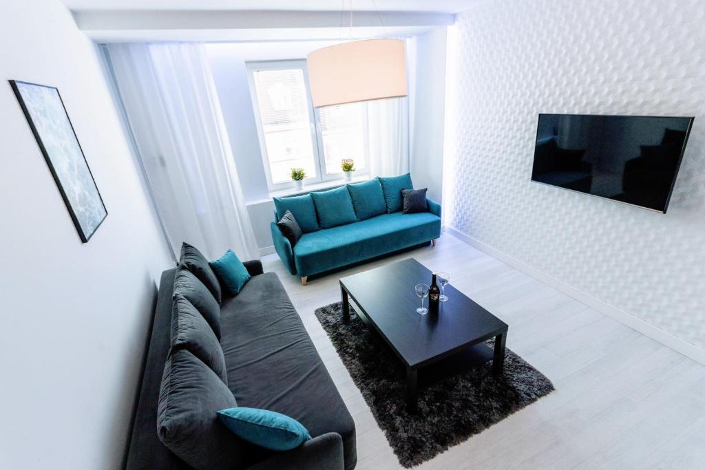 a living room with a blue couch and a coffee table at Apartment Kuźnicza Wroclaw Old Town in Wrocław
