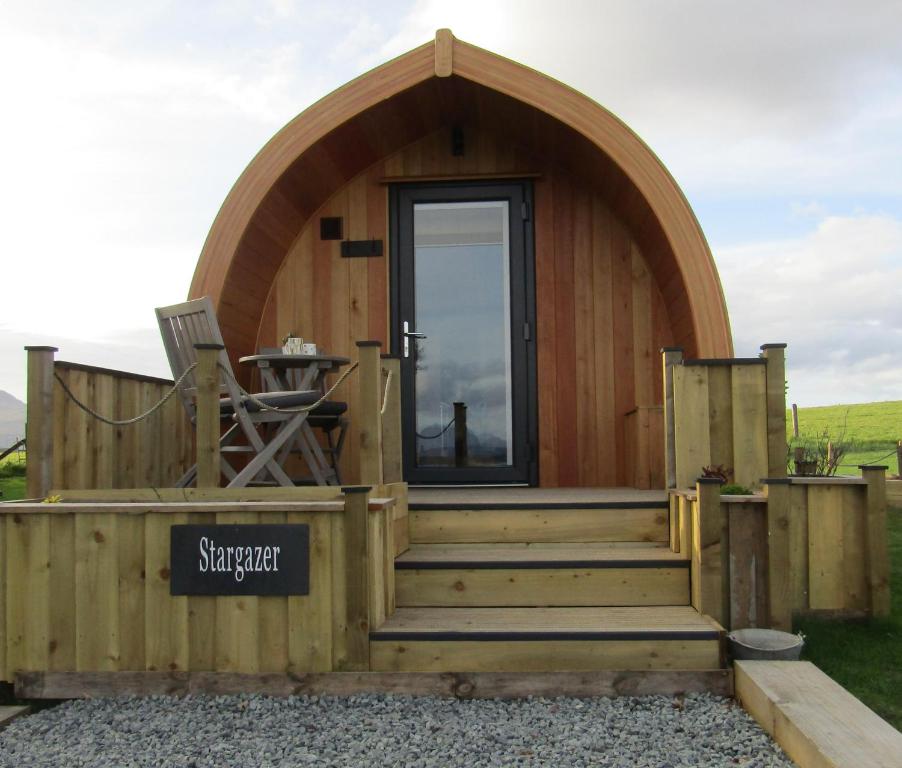 a small wooden cabin with a circular door and stairs at Harlosh Hideaways - Stargazer Pod in Harlosh
