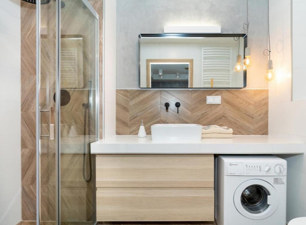 a bathroom with a sink and a washing machine at Sailor 7 Z bocznym widokiem na morze in Ustronie Morskie