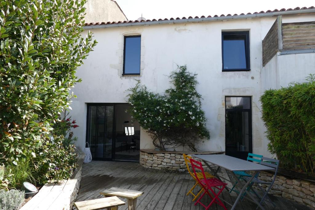 a patio with a table and chairs in front of a building at Magnifique rétaise-hyper centre le Bois-Plage-en-Ré in Le Bois-Plage-en-Ré
