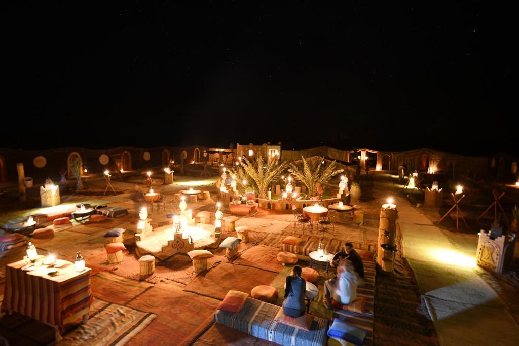 un gruppo di persone che si trovano in un cortile di notte di Desert Bivouac Mhamid a M'Hamid