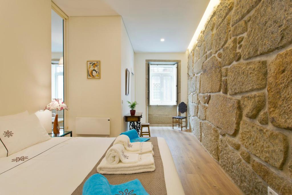 Un dormitorio con una pared de piedra y una cama en Estrela de Gaia Apartments, en Vila Nova de Gaia
