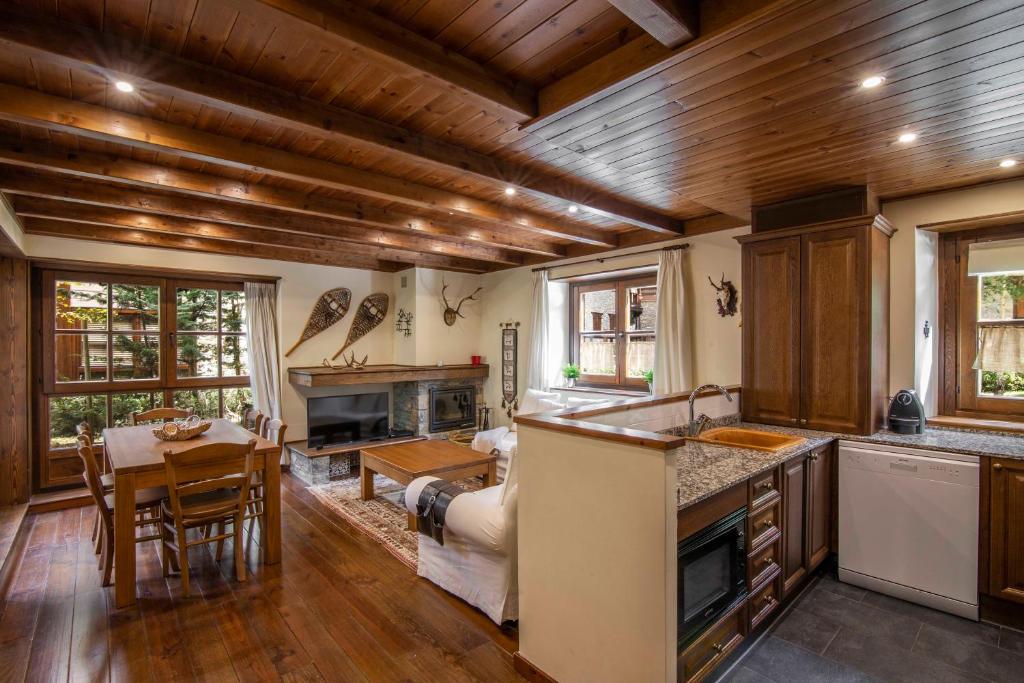 a kitchen with wooden ceilings and a dining room with a table at GERBER de Alma de Nieve in Baqueira-Beret