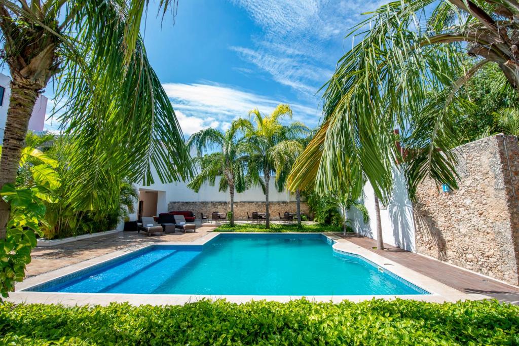 una piscina en un patio con palmeras en Hotel Embajadores, en Mérida