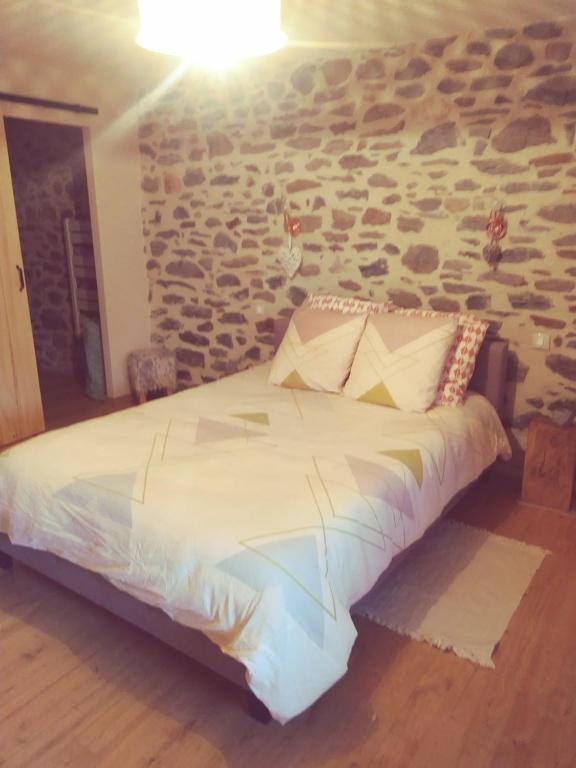 a bed in a room with a stone wall at L étable au naturel in Mauriac