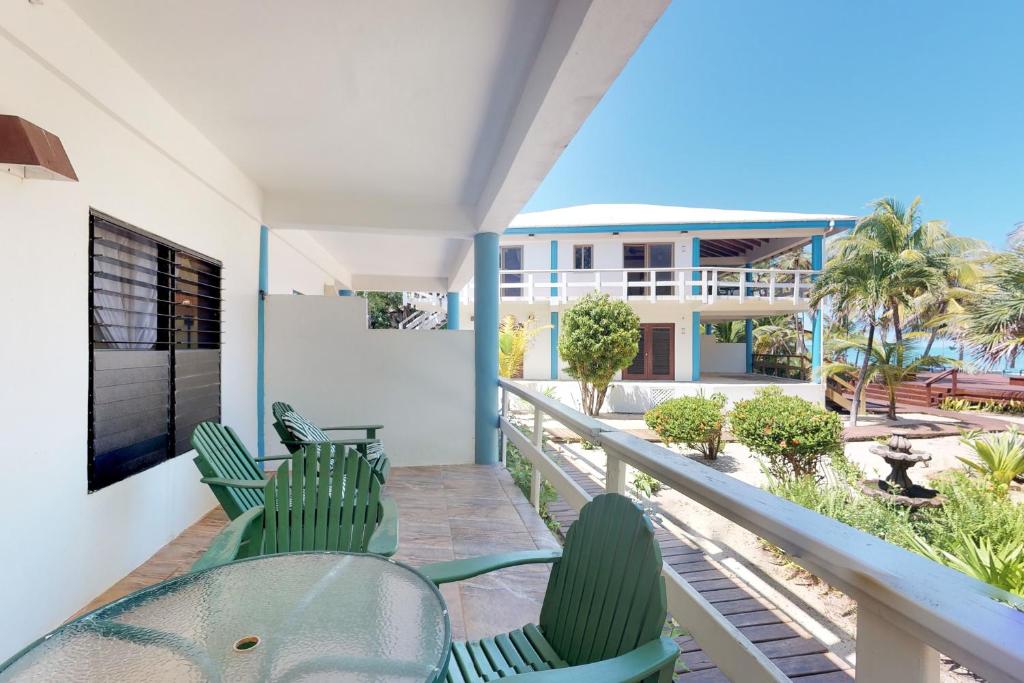 a balcony with green chairs and a view of the ocean at Condo #25 @ Beachside Villas in Placencia Village