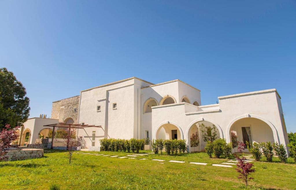 une grande église blanche avec une cour d'herbe dans l'établissement Tenuta Ermes, à Ostuni