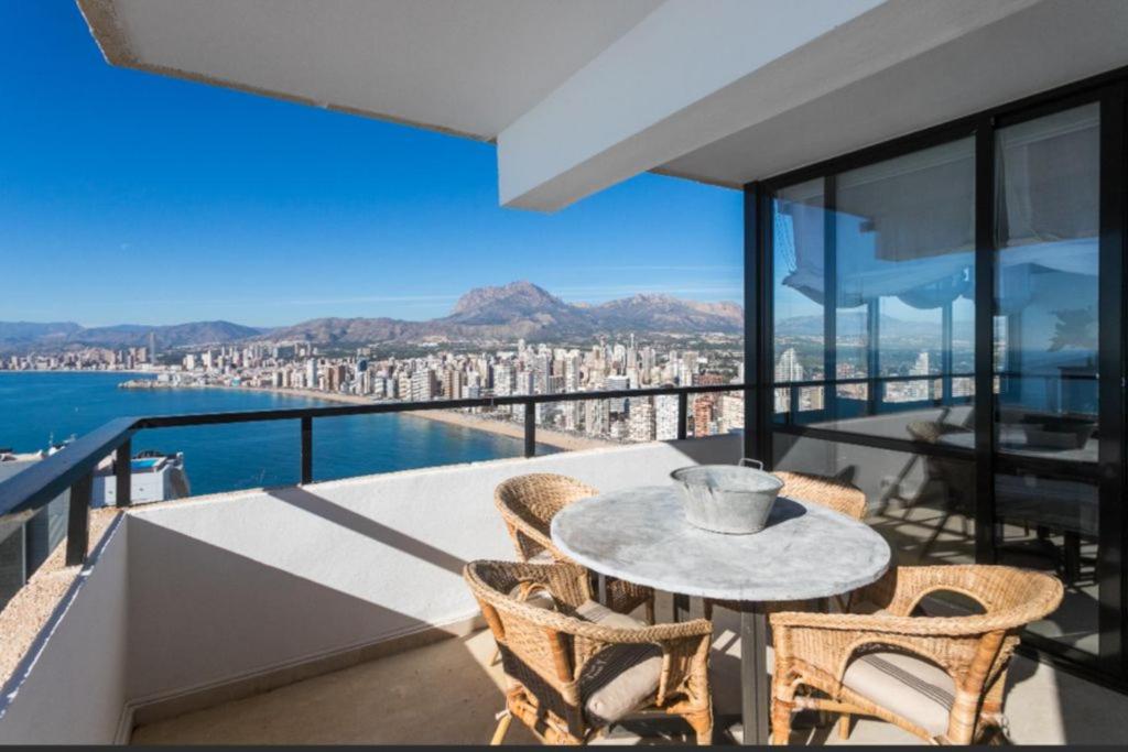 balkon ze stołem i krzesłami oraz widokiem na miasto w obiekcie ATICO BENIDORM PLANTA 25 w mieście Benidorm