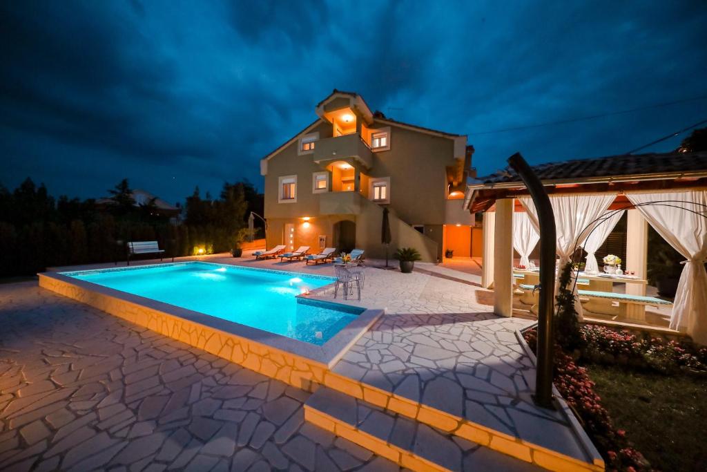 una piscina frente a una casa por la noche en Villa Kontrada, en Zadar
