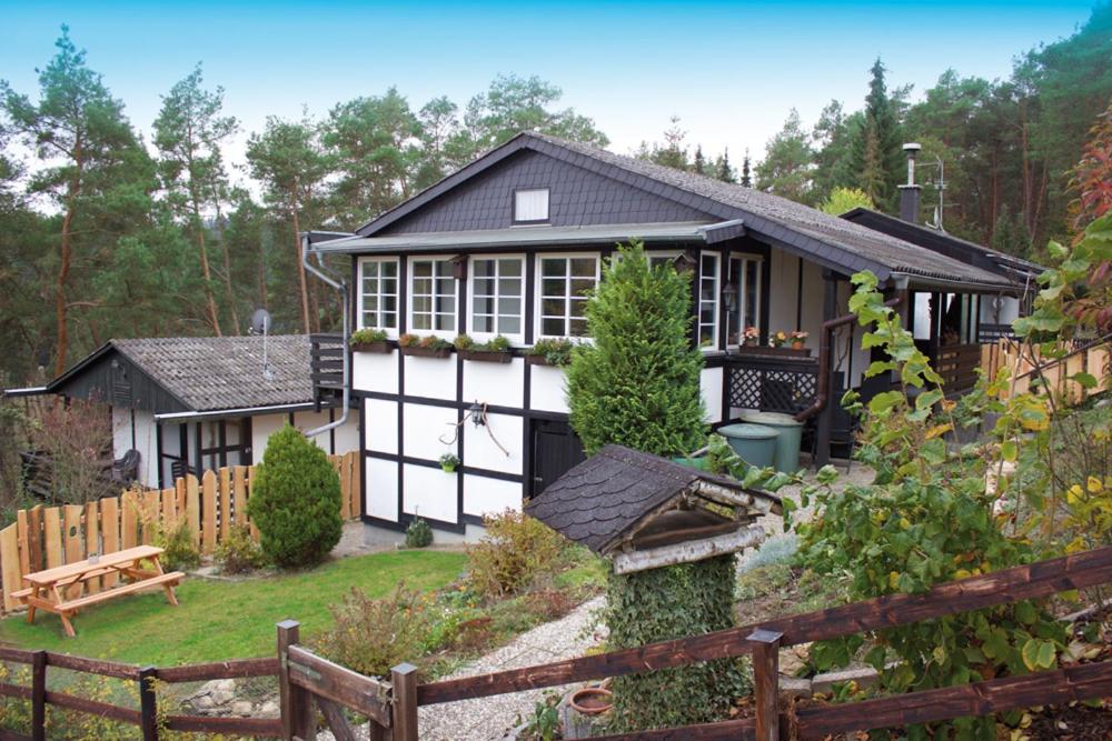 a white and black house with a wooden fence at Wolfs Ferienhaus - Natürlich Eifel in Blankenheim