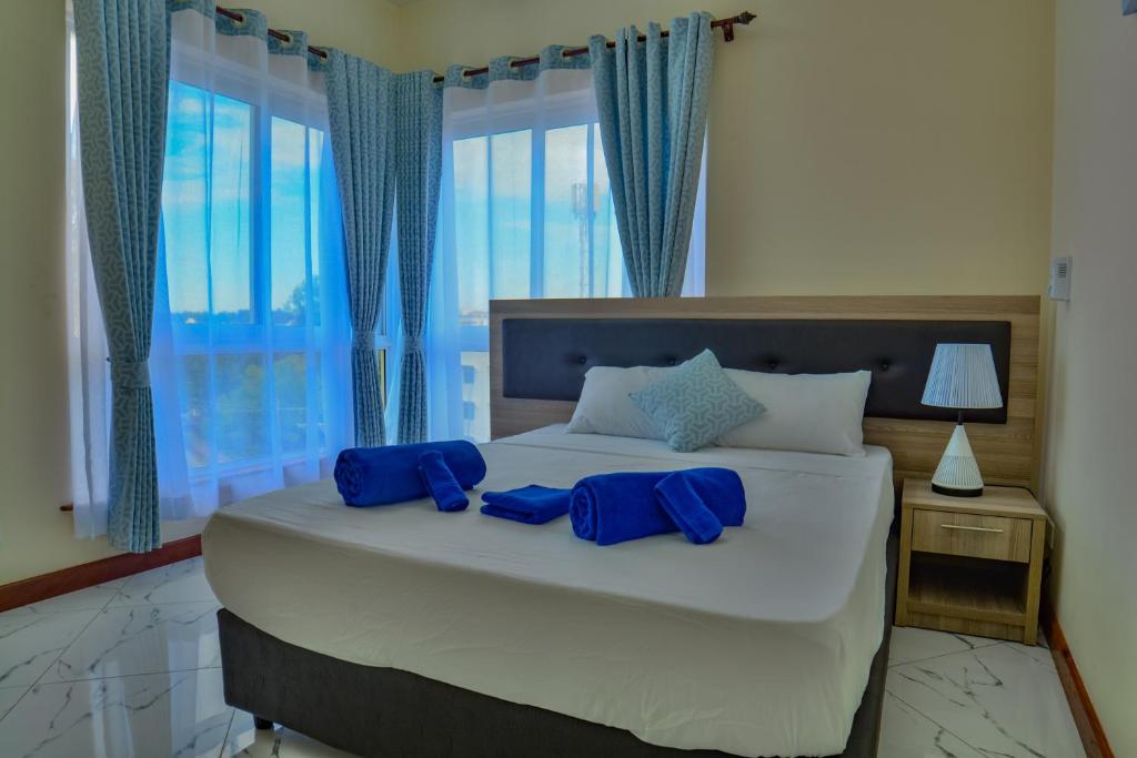 a bedroom with a large bed with blue pillows on it at Fenns Cozy Apartment - Nyali in Mombasa