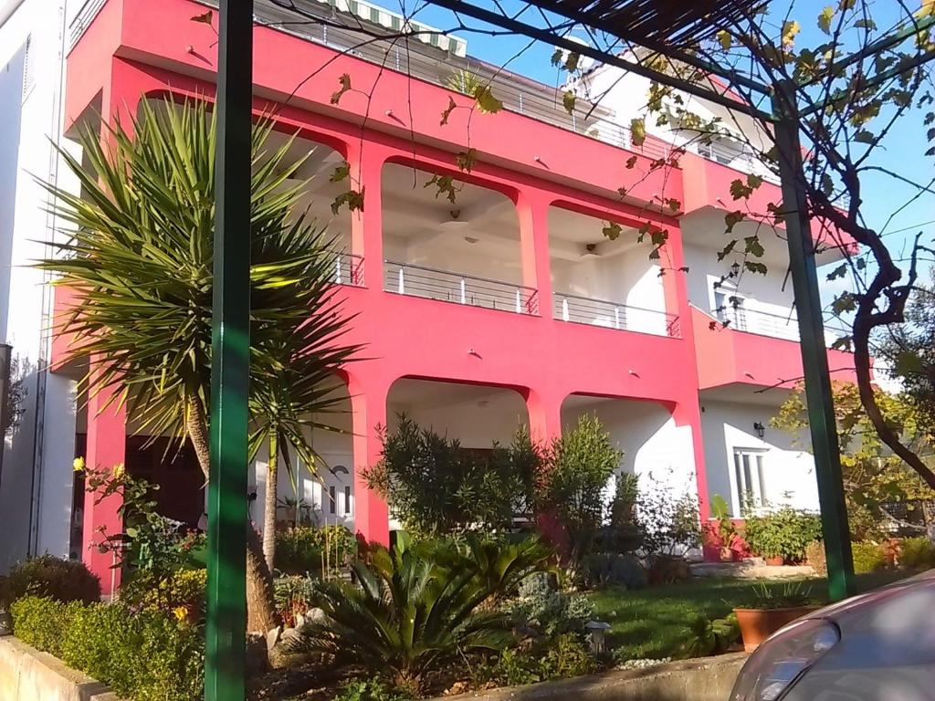 a pink building with trees in front of it at Apartments Mare - 30m from beach in Seget Vranjica