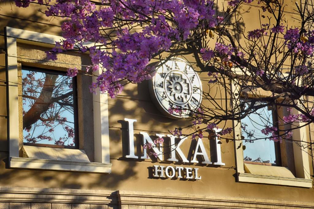 un reloj al lado de un hotel con flores púrpuras en Hotel Inkai en Salta