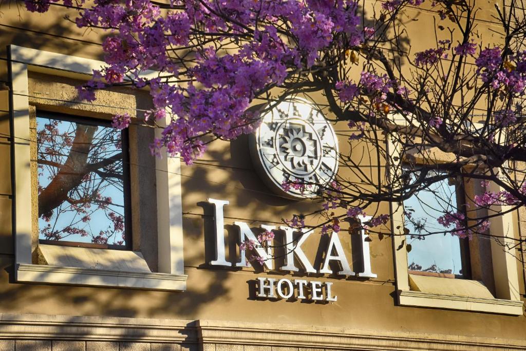 eine Uhr an der Seite eines Hotels mit lila Blumen in der Unterkunft Hotel Inkai in Salta