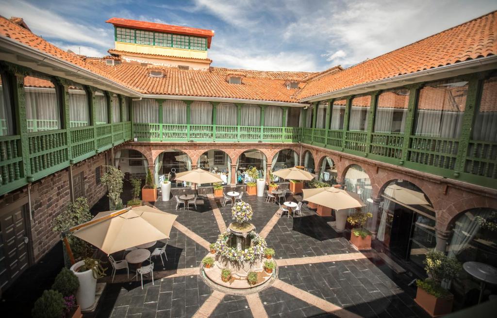 Aranwa Cusco Boutique Hotel في كوسكو: ساحة مع طاولات ومظلات في مبنى