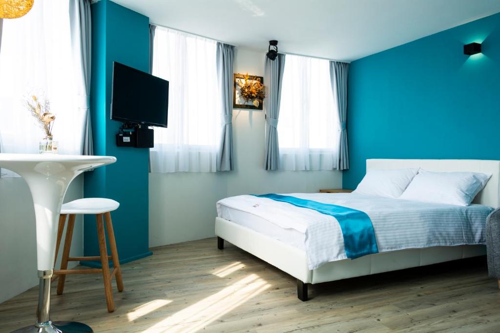 a blue bedroom with a bed and a television at Mulan Light Inn in Tainan