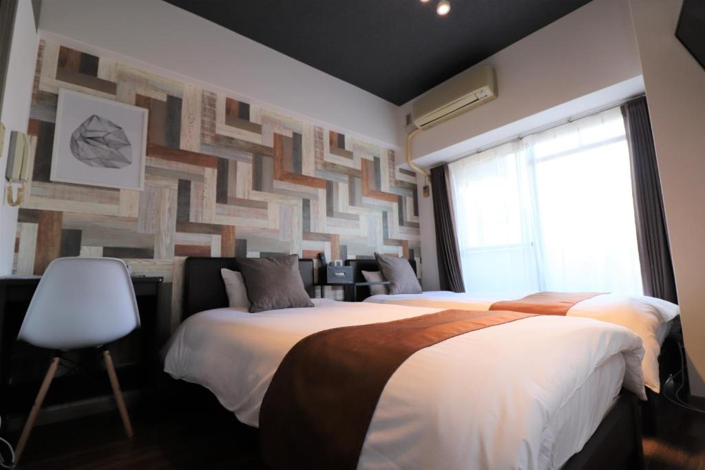 a bedroom with two beds and a wall with a pattern at Forest Inn Fukuoka -previously Pure Tenjin- in Fukuoka